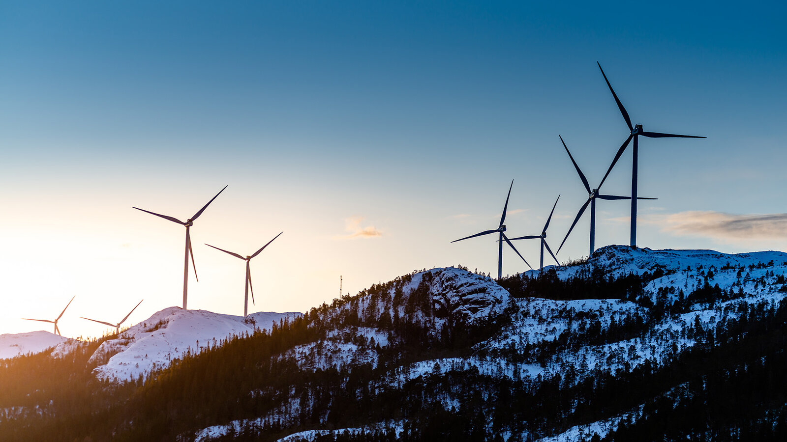 vindmøller på en åskam, med solnedgang i bakgrunnen