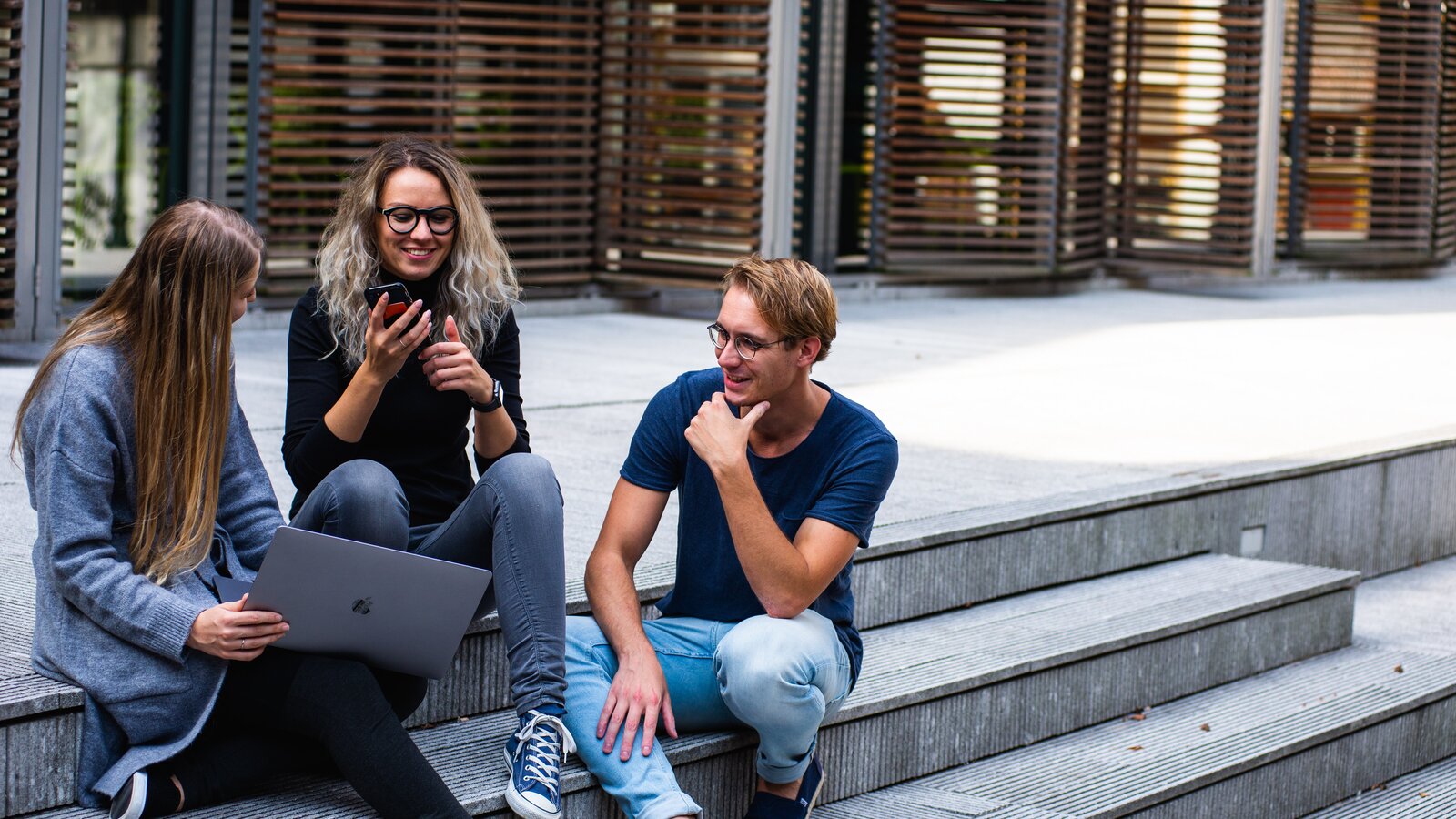 three-persons-sitting-on-the-stairs-talking-with-each-other