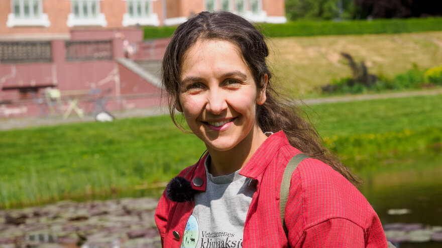 På bildet vises veterinærstudent Ida Beate Løken, hun har rød skjorte og en t-skjorte det står "Veterinærenes klimaaksjon" på.