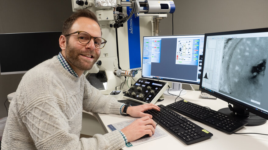 Fredrik Strebel Skedsmo foran pc og elektronmikroskop på NMBUs Imaging Centre.
