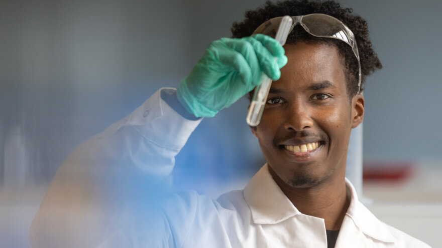 Ibrahim Adan holder opp et reagensrør inne på laboratoriet på fakultet for kjemi, bioteknologi og matvitenskap