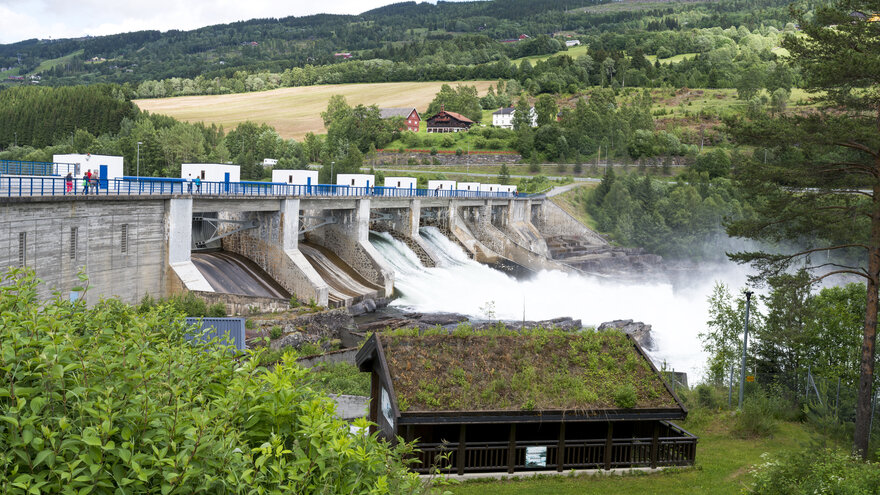 Lite vannkraftverk med hytte i forgrunnen.