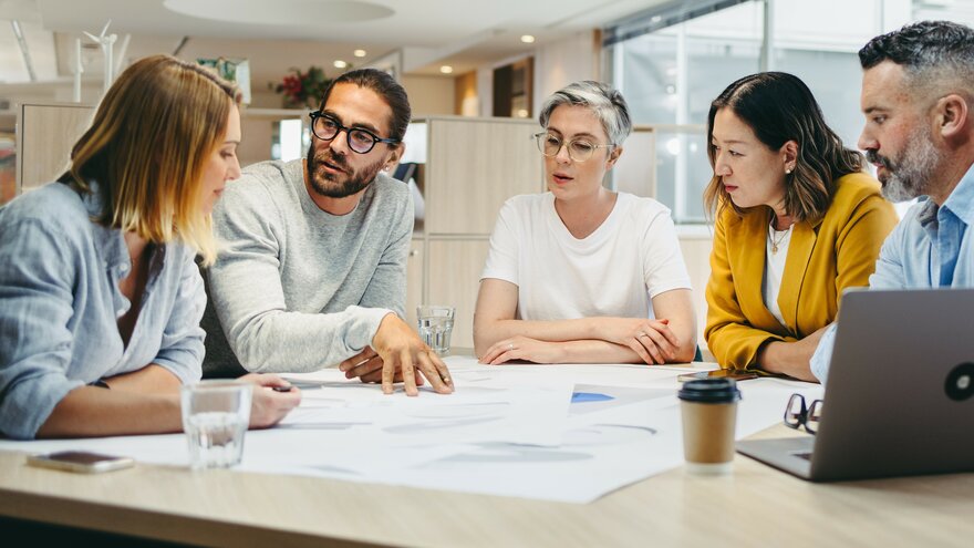 Arbeidsmøte med student på internship og kollegaer i vertsvirksomheten rundt et bord.