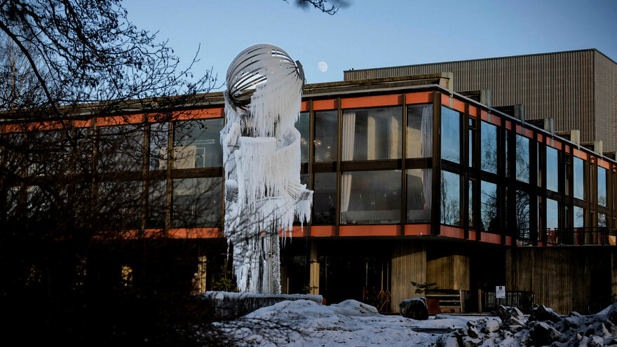 Carl Nesjar (1920-2005) Fontenen/skulpturen sto ferdig i 1971 ved Auditorium Maximum. Fontenen er en stålkonstruksjon som utnytter vannspillet i sommerhalvåret, og om vinteren dekkes den av istapper og krystaller. Carl Nesjar var maler, grafiker og bill