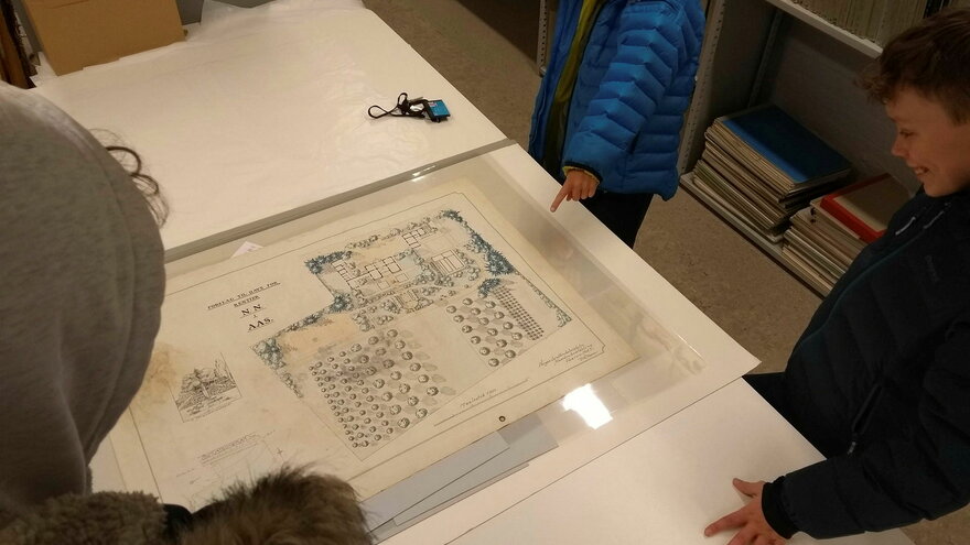 Arkivet knytter dagens samfunn til fortiden (På bildet: Barn ser på historiske planskisser).