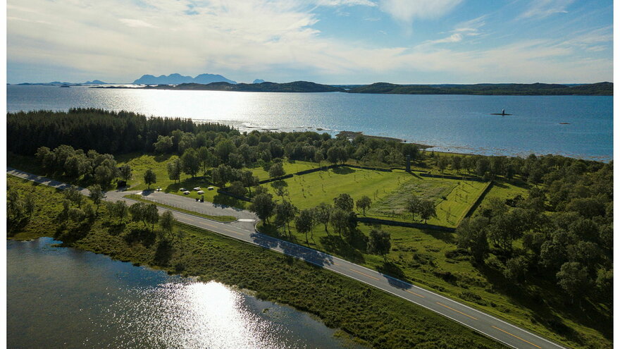 Tjøtta Krigskirkegård med hav på to sider og himmel i bakgrunnen.