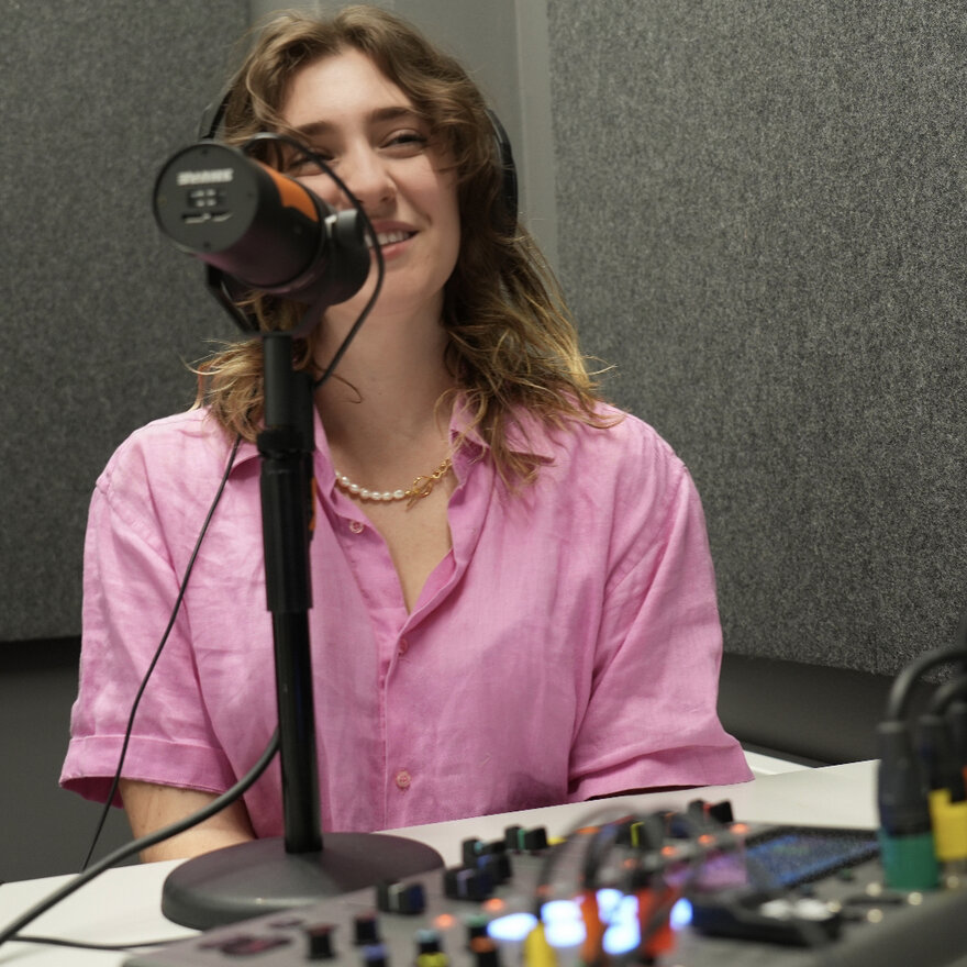 Smilende student som lager podcast i studio