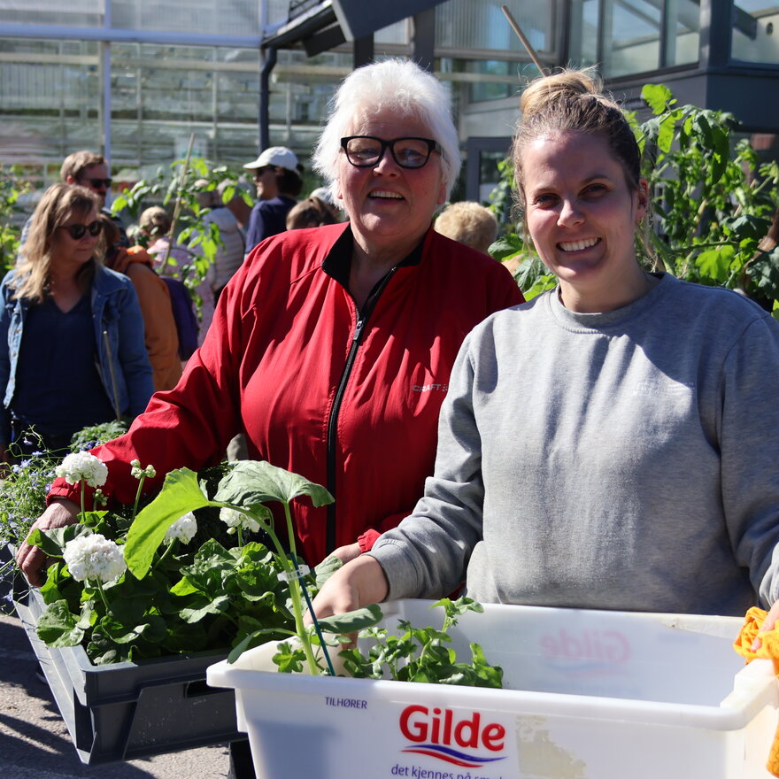 To kunder med hver sin kasse i hendene med blomster de skal kjøpe