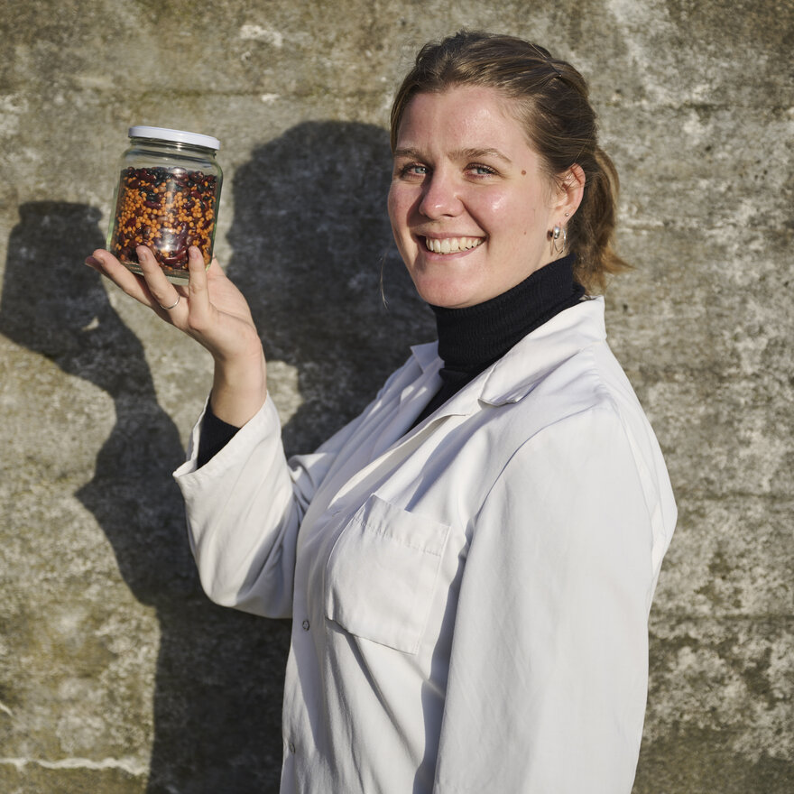 Charlotte Bauer Munch-Andersen utenfor laben, hun holder opp et glass med prøver
