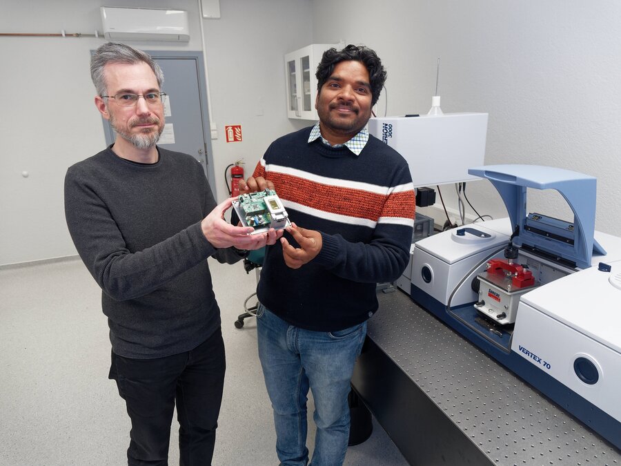 Boris Zimmermann (til venstre) og Nageshvar Patel har begynt å bygge forstadiet til en håndholdt skanner. Den lille saken som de holder opp, skal erstatte den store maskinen til høyre på bildet.