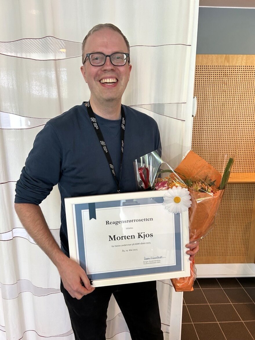 Morten Kjos holder opp diplom og blomster etter å ha blir kåret til semesterets beste underviser av studentene på KBM